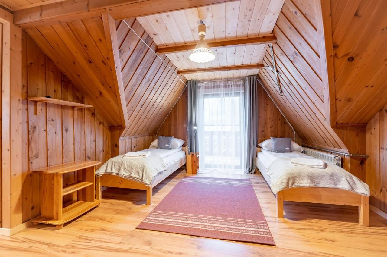 Pokój na poddaszu w drewnie z dwoma łóżkami i drzwiami na balkon